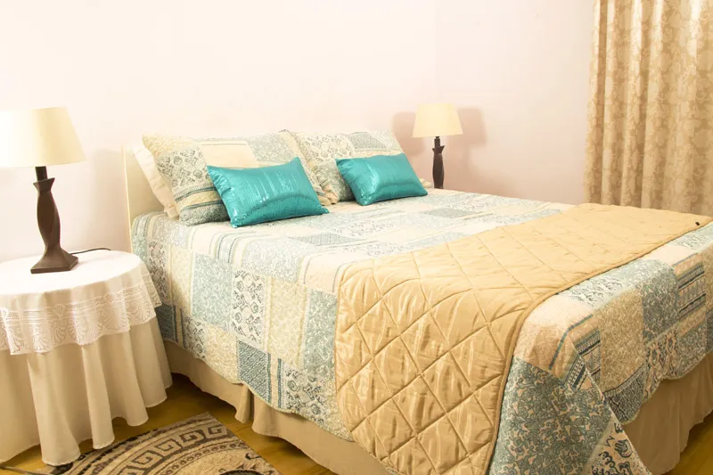 Bedroom with a neatly made bed two bedside lamps and patterned curtains