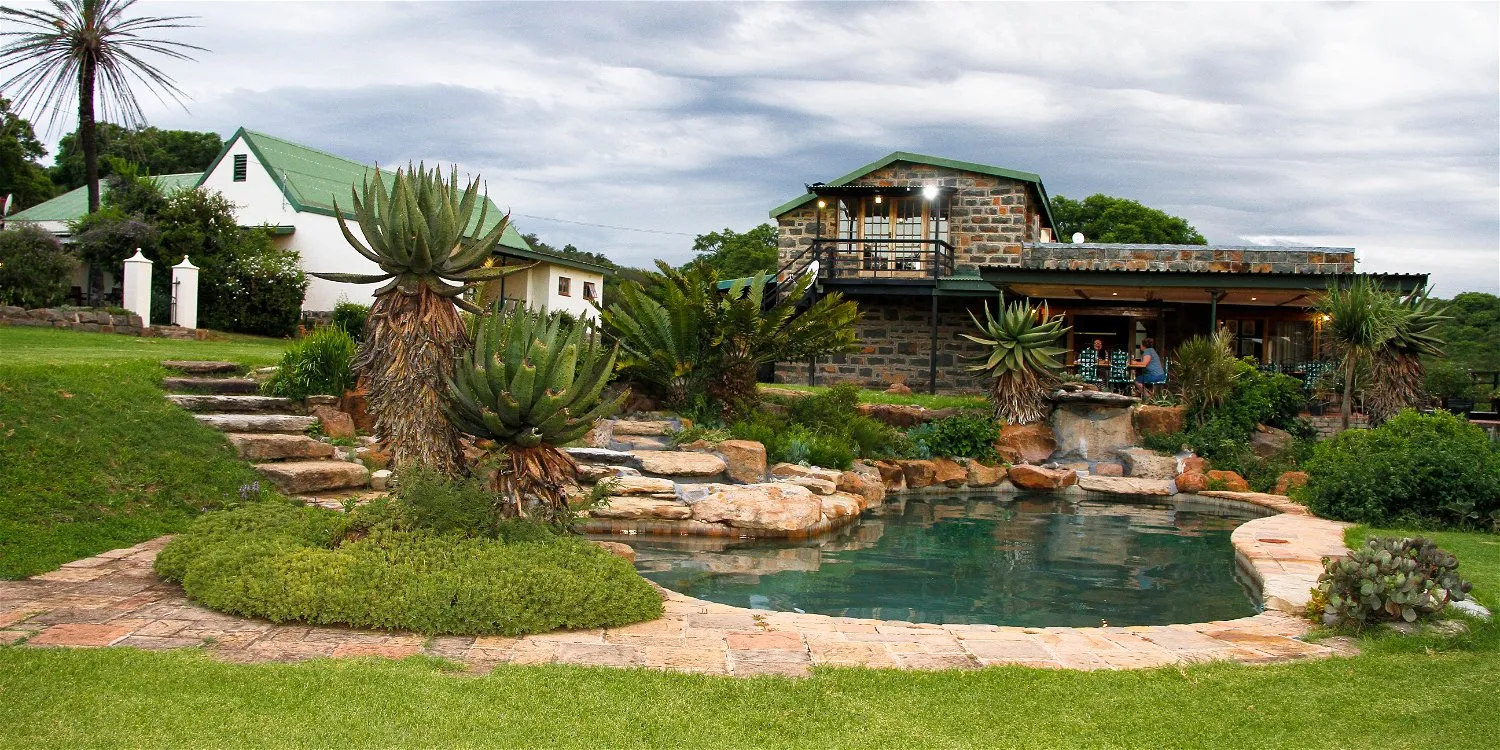 House with a pool lush garden and stone waterfall in a scenic setting