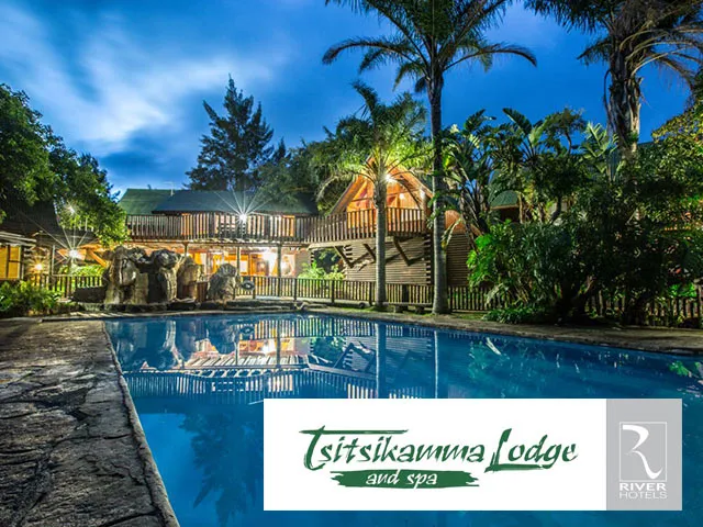 Evening view of Tsitsikamma Lodge with pool and illuminated wooden cabins