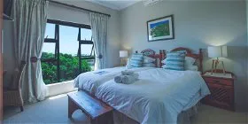 Bright bedroom with large windows white bed wooden furniture and garden view