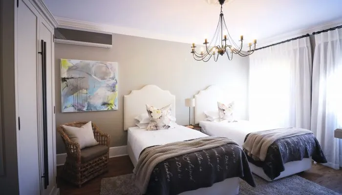 Two twin beds in a bright bedroom with a chandelier and abstract art