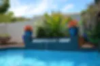 Blurry image of a swimming pool with plants and pots in the background