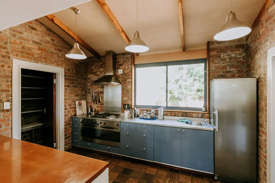 Modern kitchen with blue cabinets stainless steel appliances and brick walls