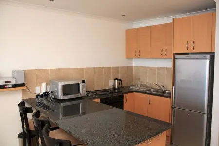 Modern kitchen with black countertops wooden cabinets microwave and refrigerator