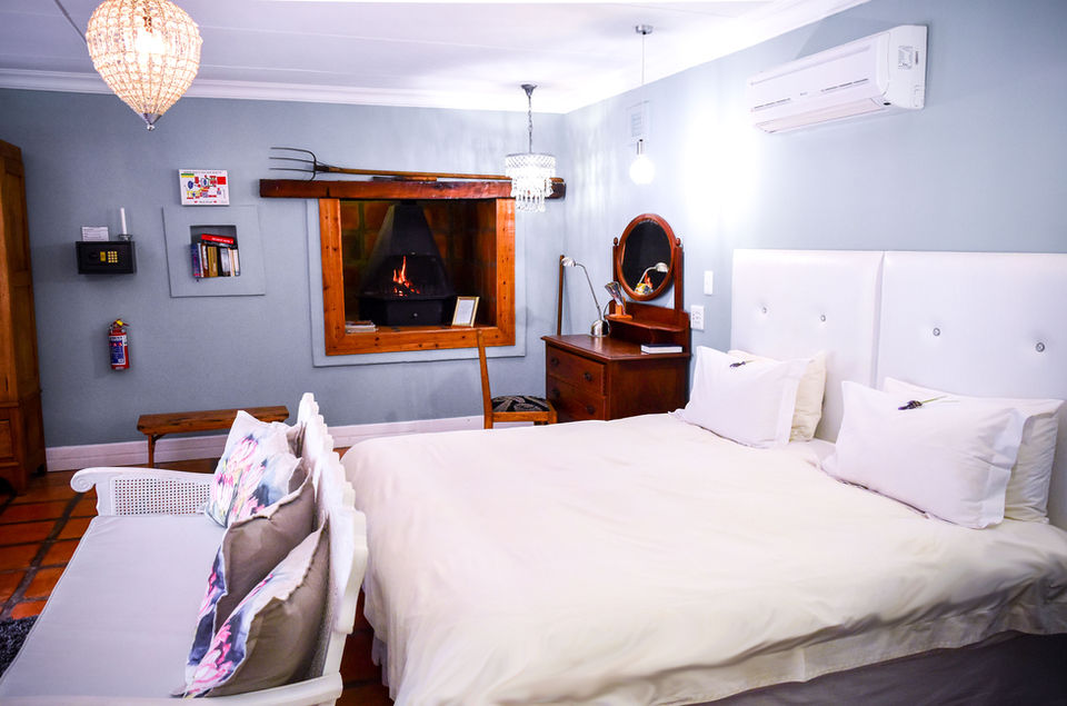 Cozy bedroom with white bed, fireplace, and vintage decor.