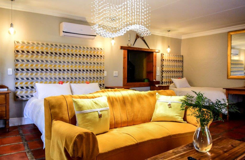Yellow sofa and bed in a cozy, modern bedroom with geometric wall art.