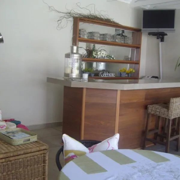 Wooden bar with shelves stools and a TV in a cozy room