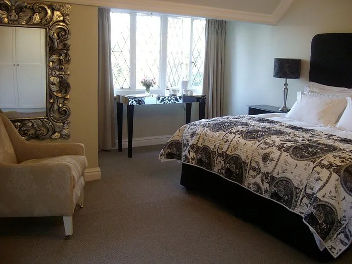 Bedroom with large bed ornate mirror armchair and window with curtains