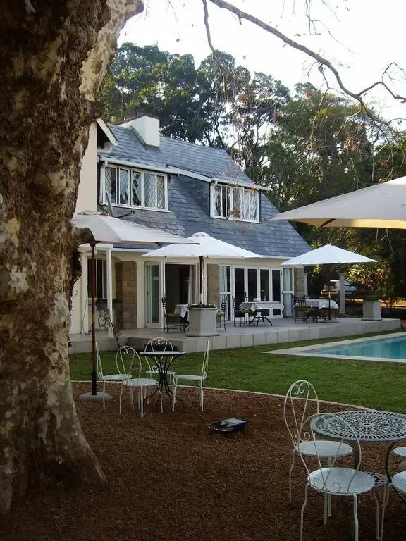 Large house with patio pool and outdoor seating area surrounded by trees