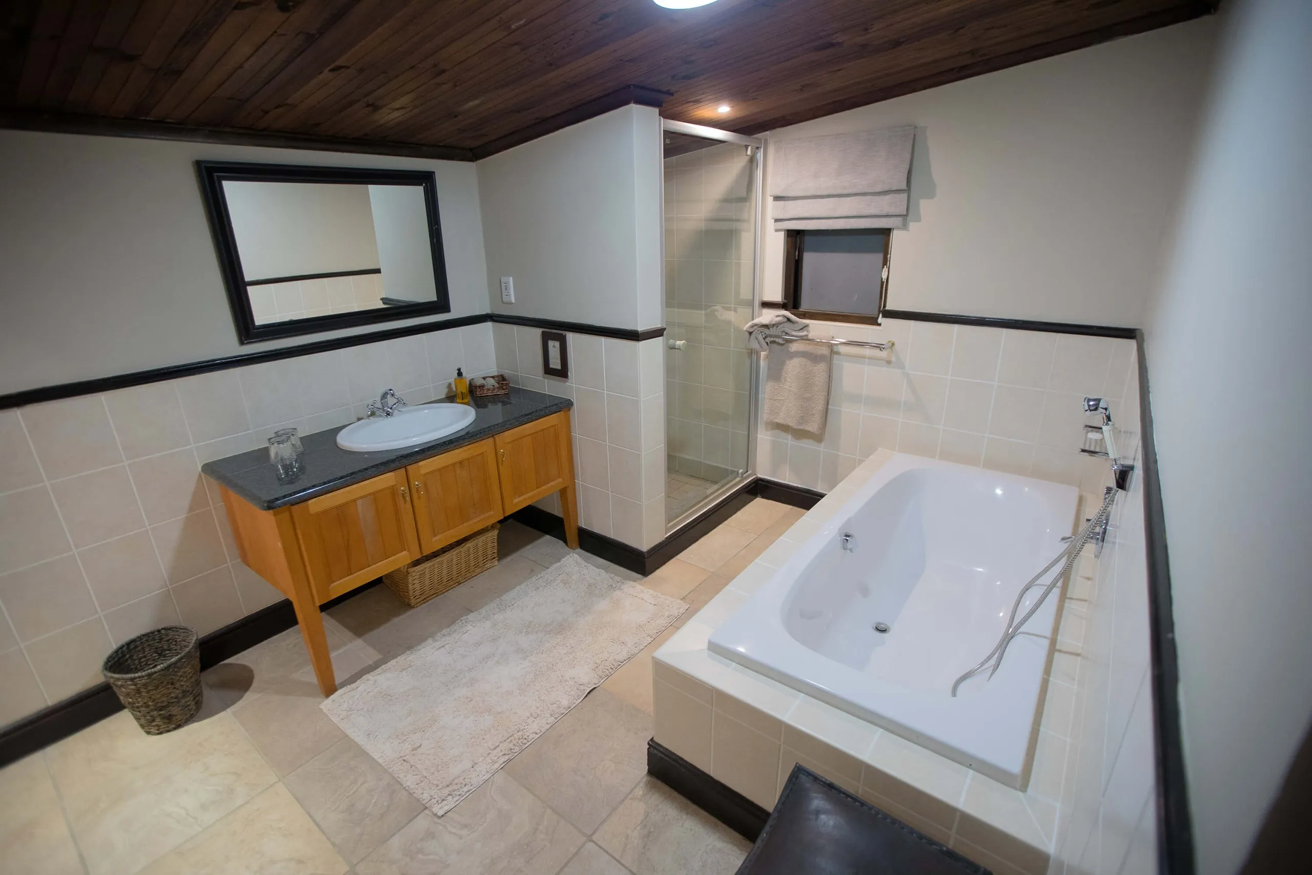 Modern bathroom with wooden vanity bathtub shower and tiled walls