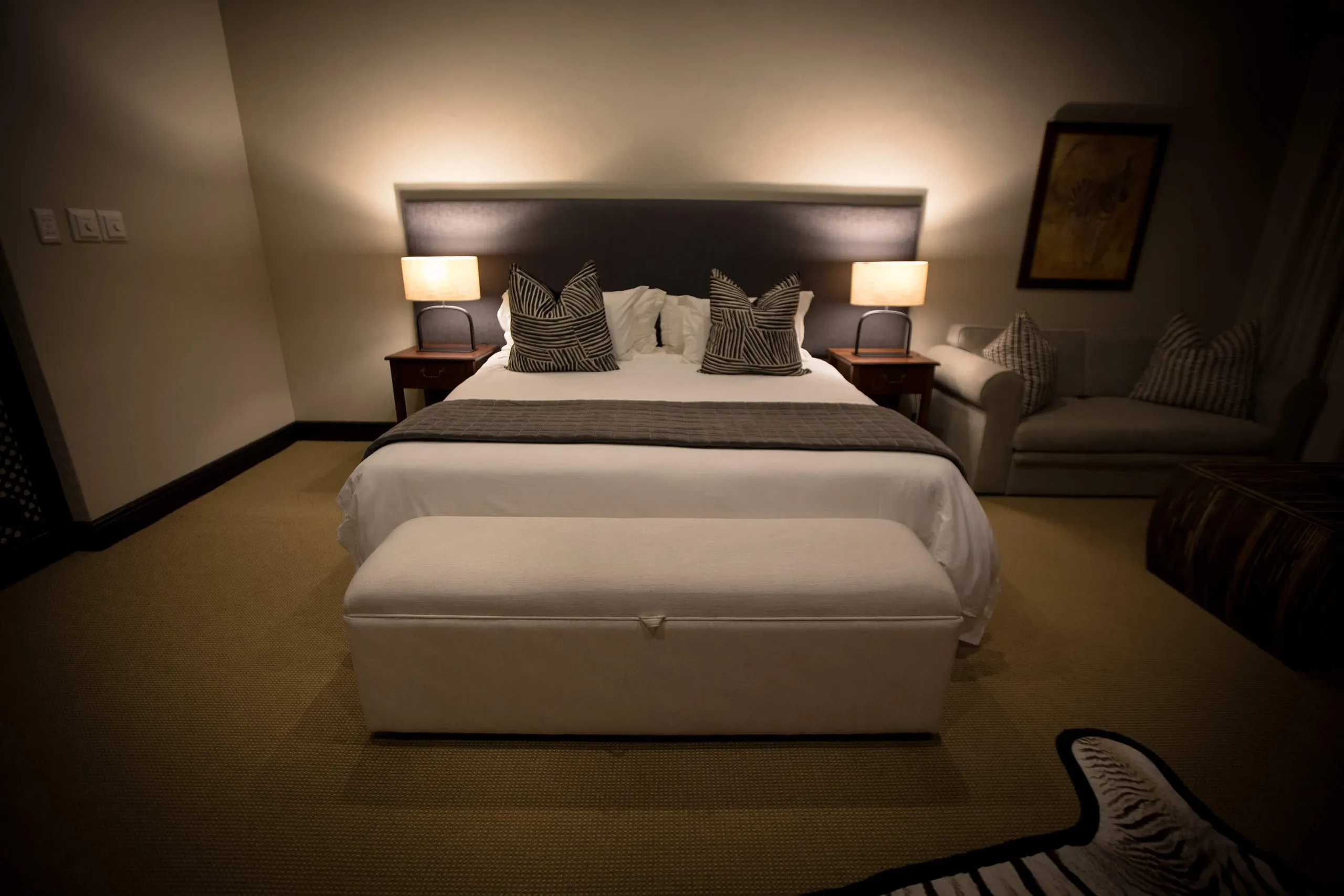 Dimly lit bedroom with a large bed side tables and a sofa