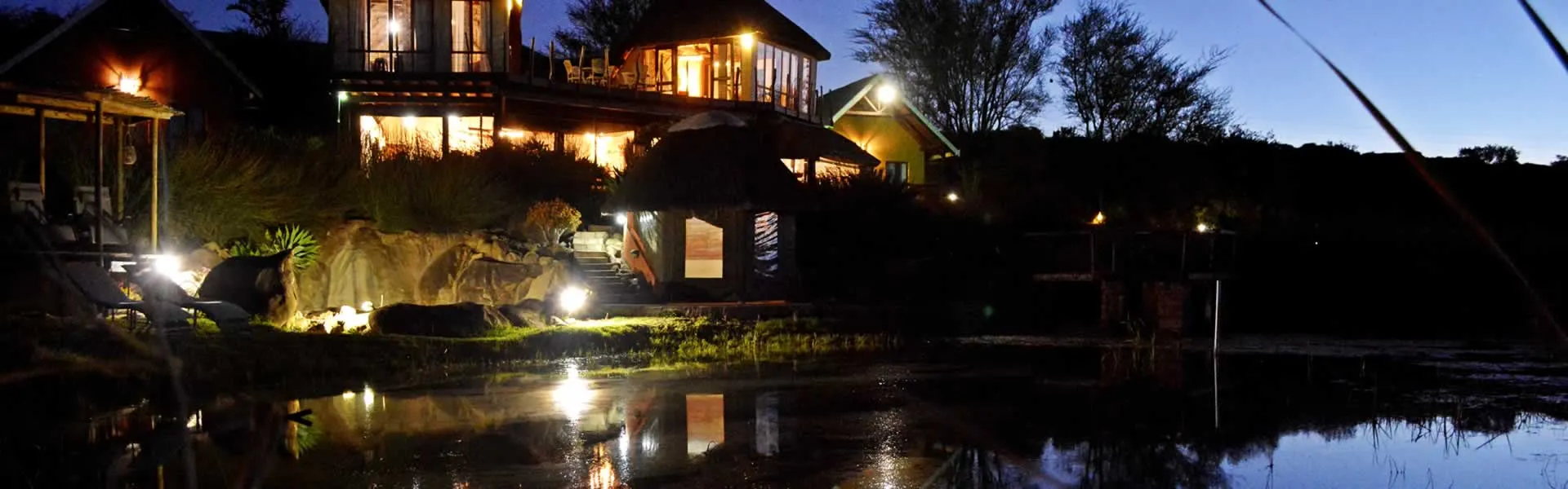 Night view of illuminated houses by a lake with reflections on water