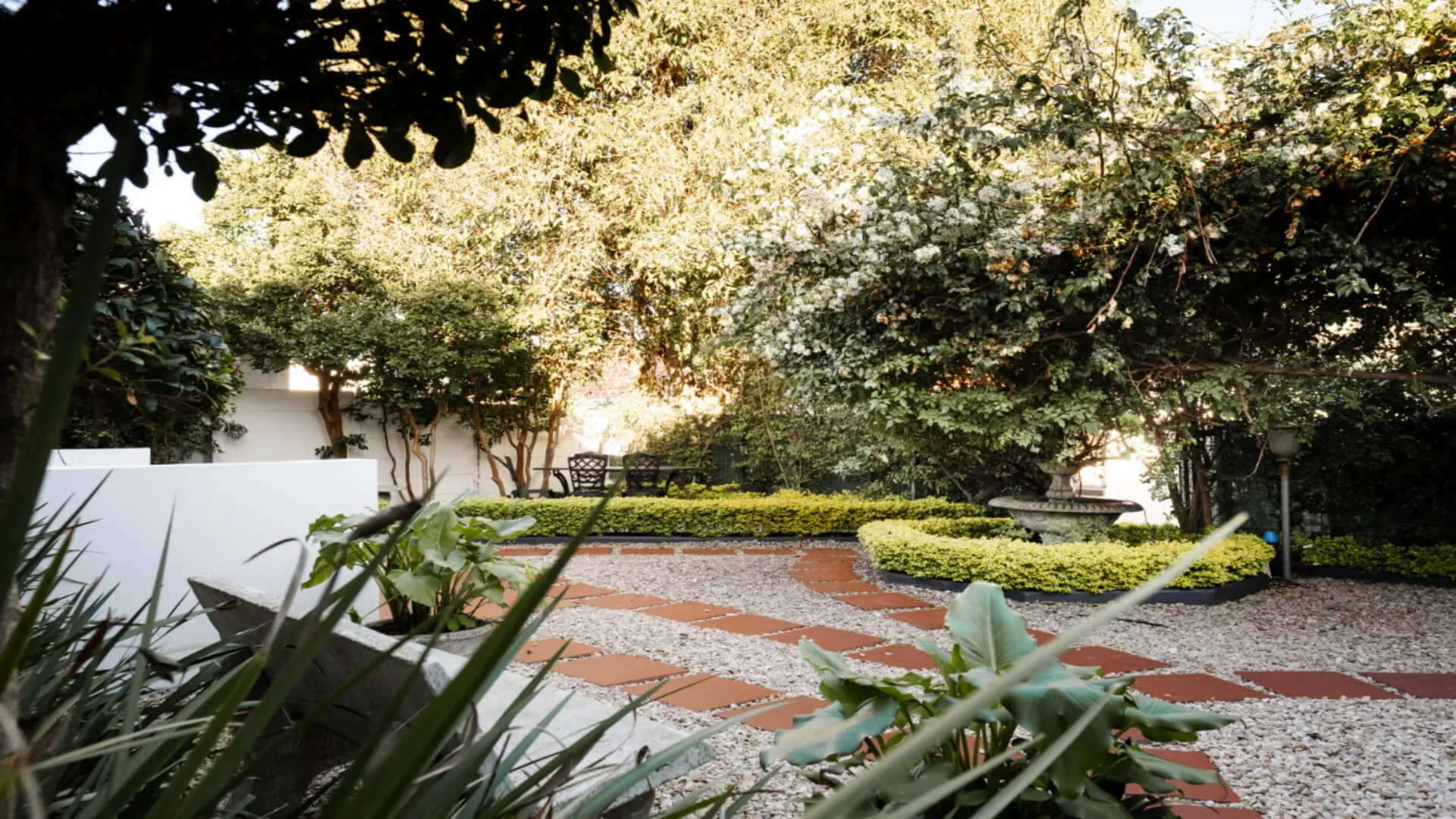 Garden with brick path green plants and trees in a sunny setting