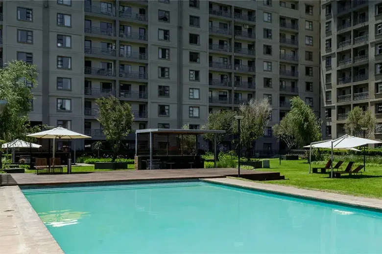 Swimming pool with lounge chairs umbrellas and surrounding apartment buildings