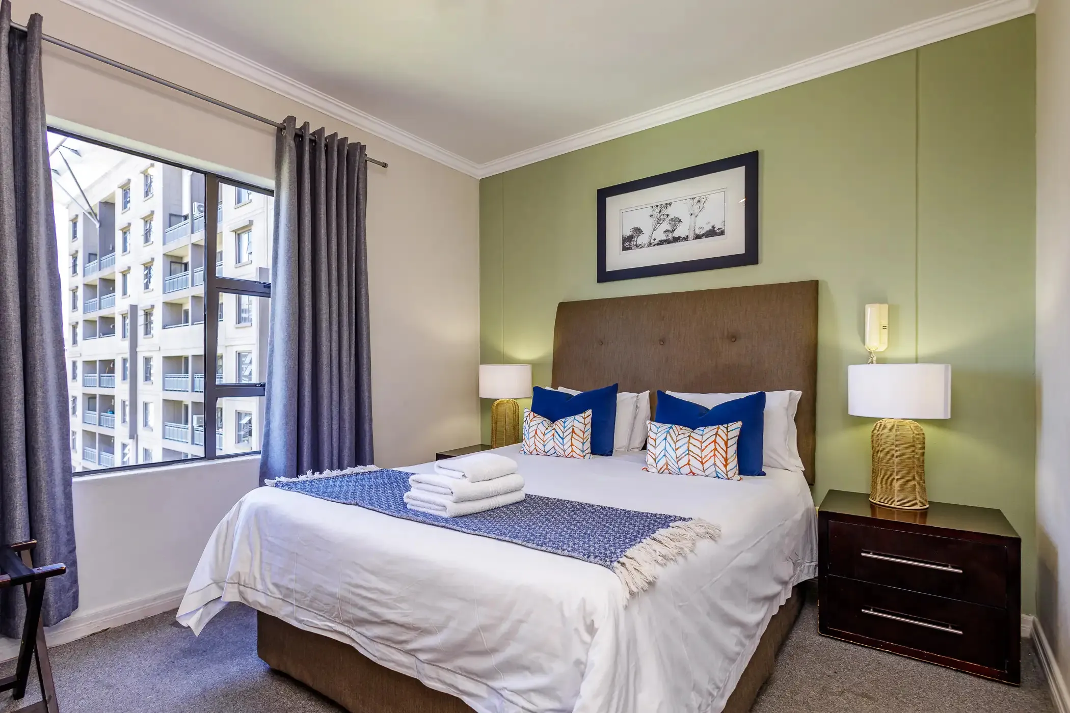 Modern bedroom with a large bed blue pillows and bedside lamps near a window
