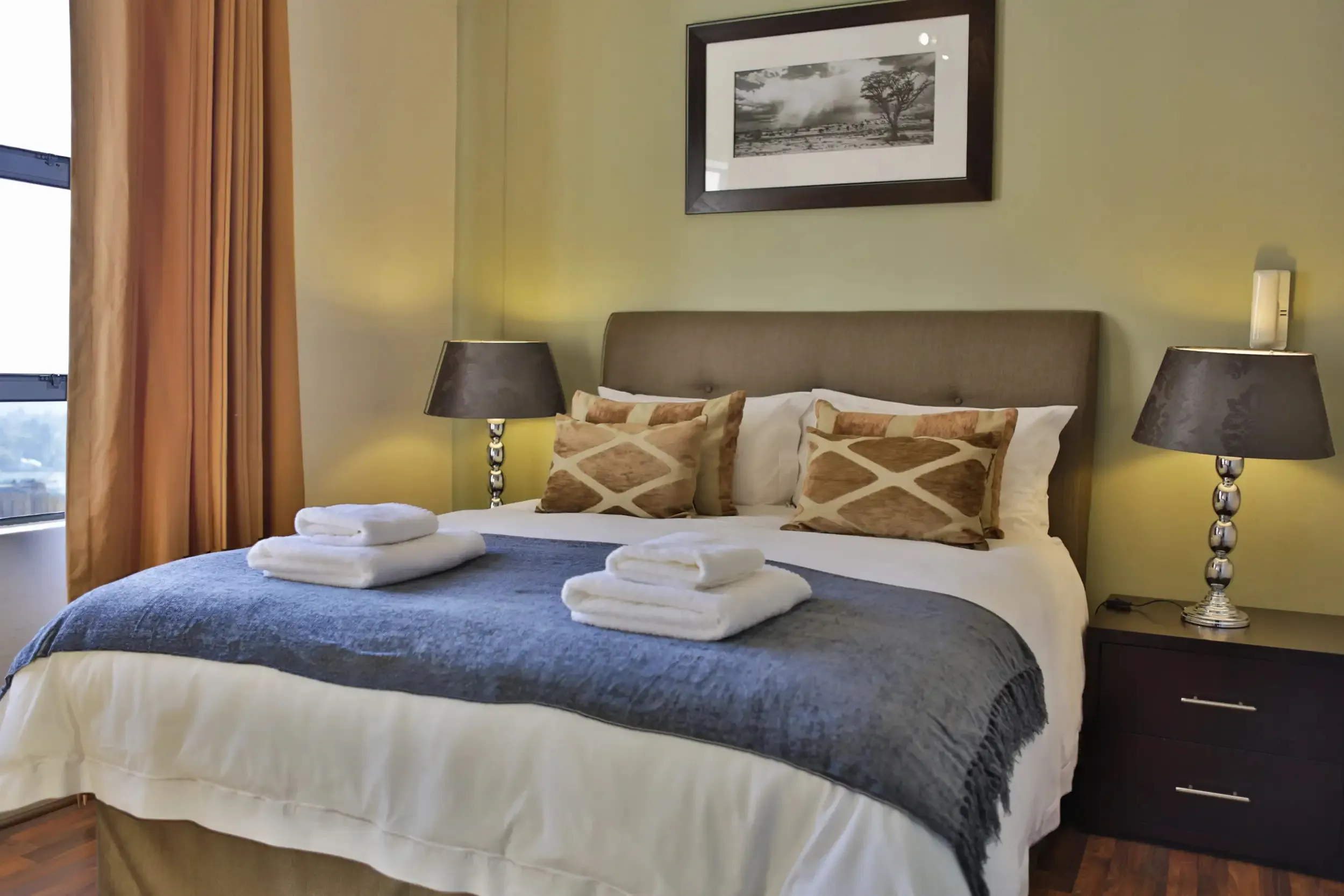 Cozy bedroom with neatly made bed two bedside lamps and a framed picture