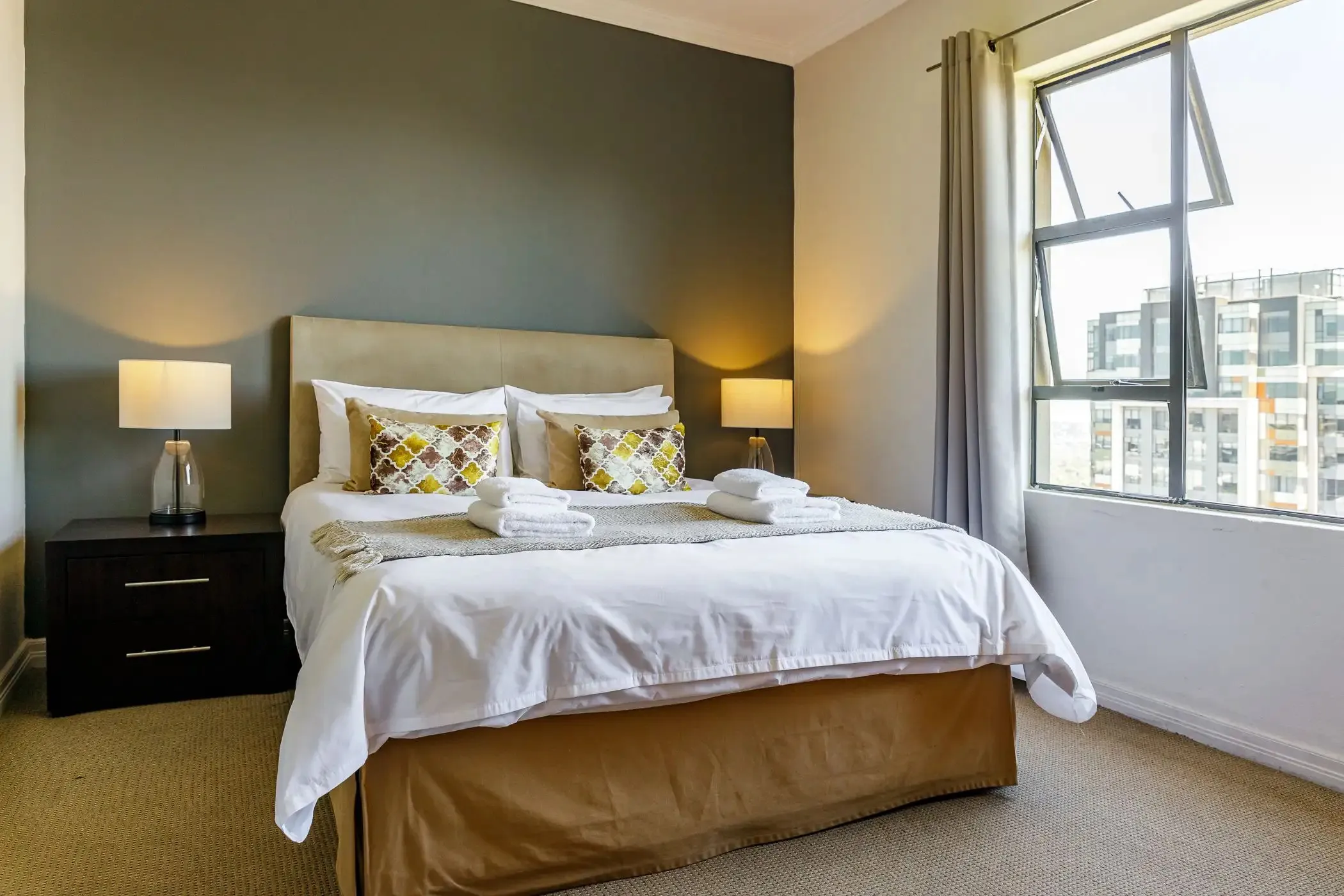 Modern bedroom with a large bed bedside tables lamps and large windows