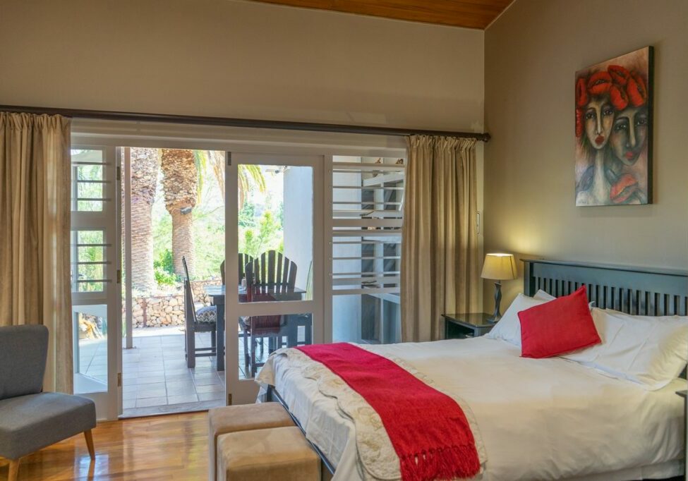Bedroom with large bed, red throw, and open patio view.