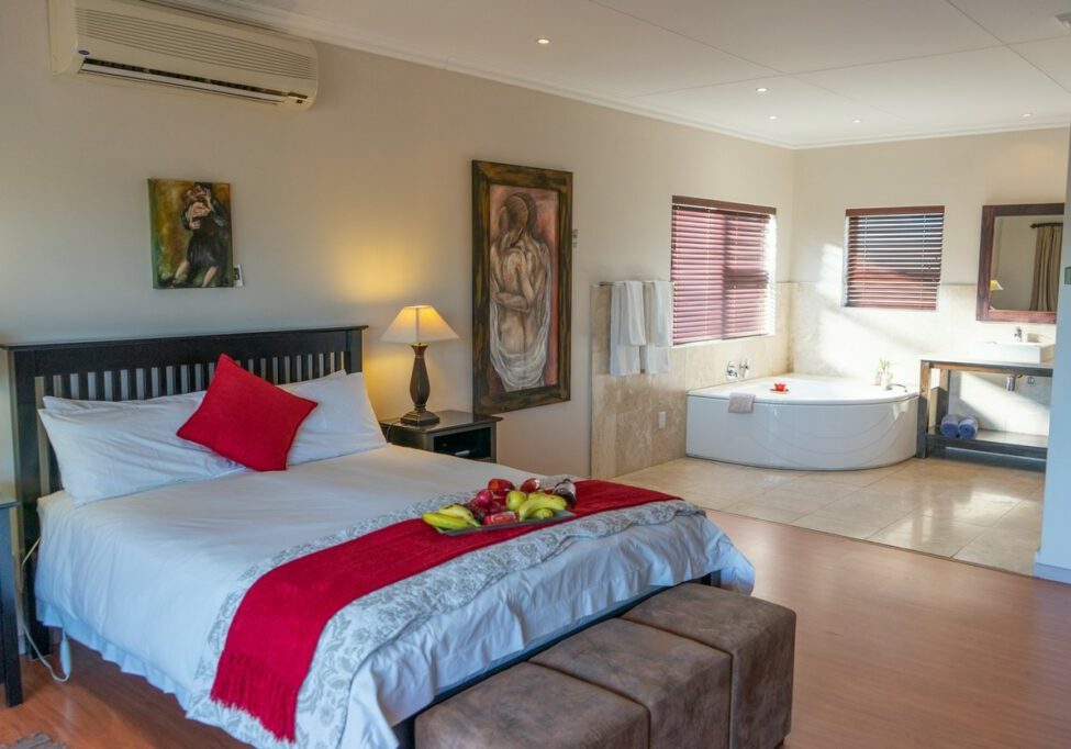 Bedroom with a bed, bathtub, and artwork on the wall.