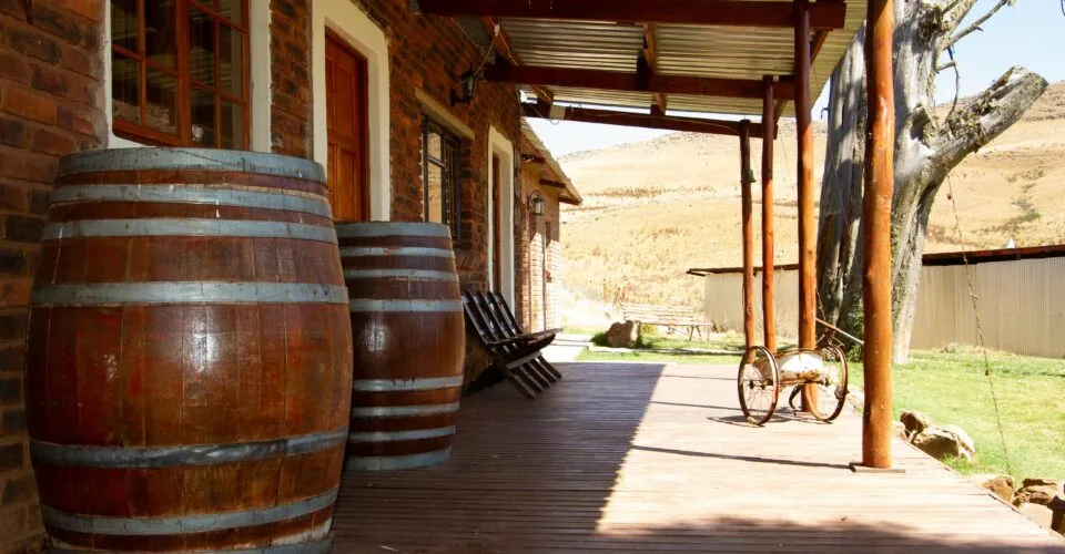 Wooden barrels on a porch with chairs overlooking a rural landscape