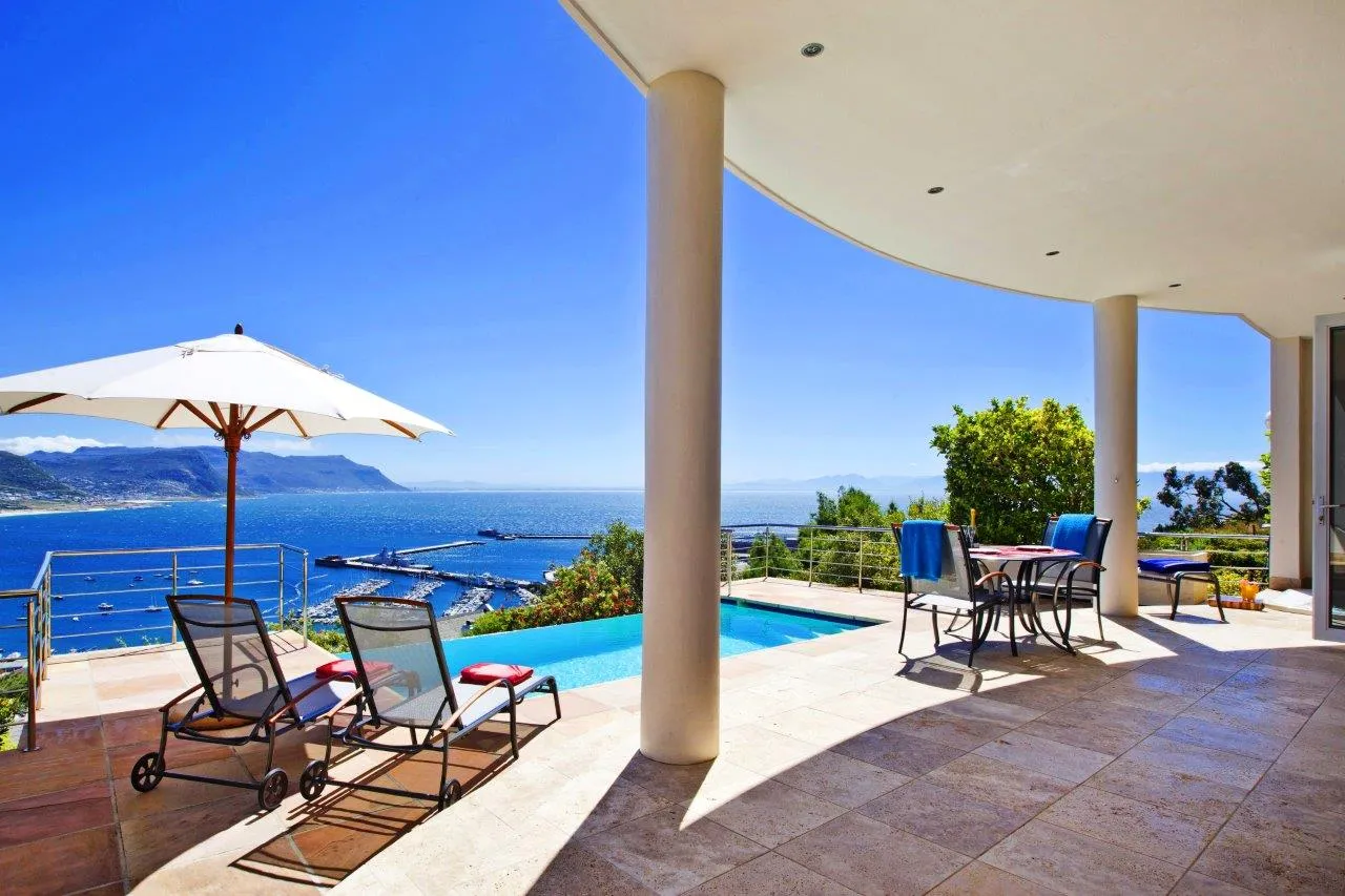 Patio with lounge chairs dining table and ocean view under a blue sky