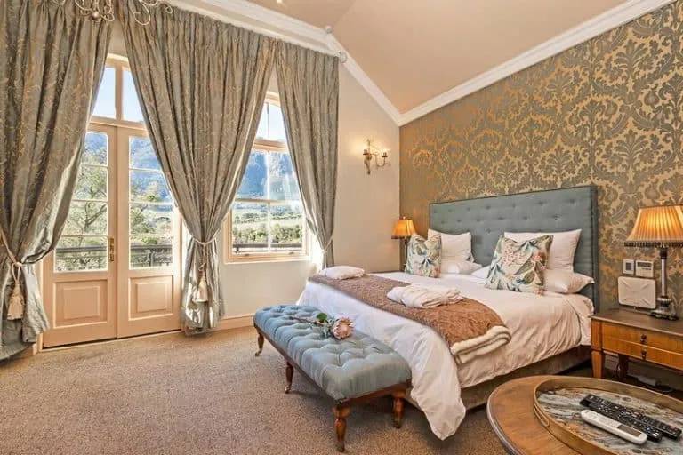 Elegant bedroom with large bed patterned wallpaper and scenic window view