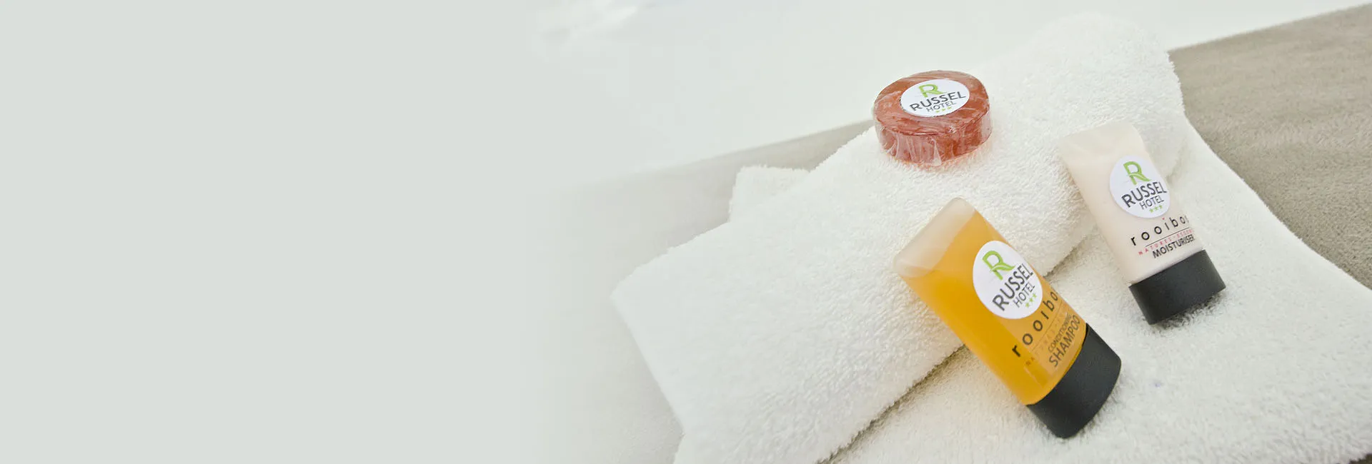 Hotel toiletries including soap shampoo and conditioner on a white towel