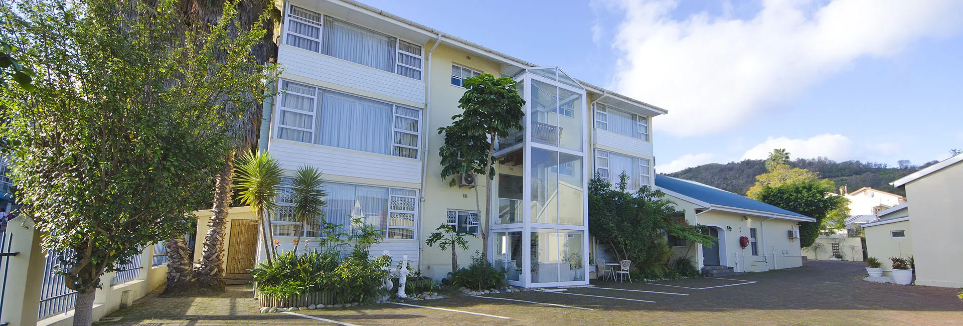 Modern white apartment building with greenery and clear blue sky in the background