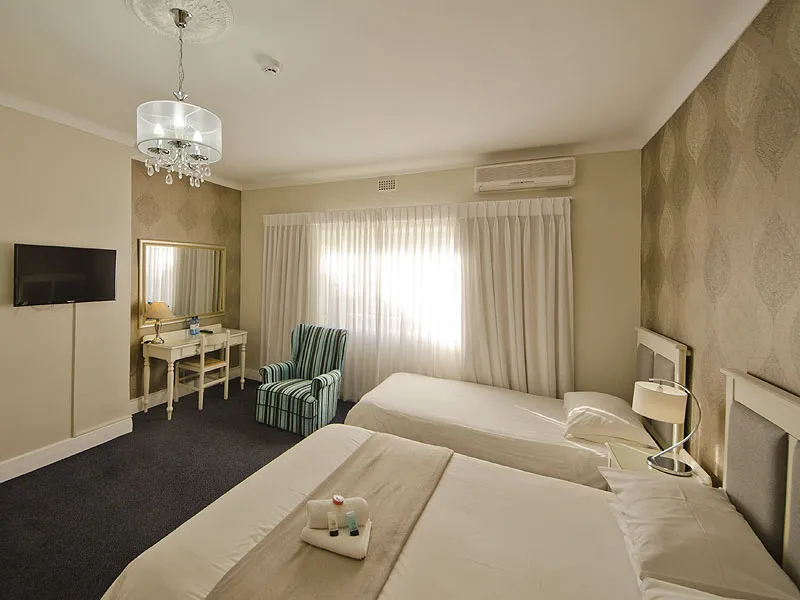 Hotel room with two beds armchair vanity and wallmounted TV