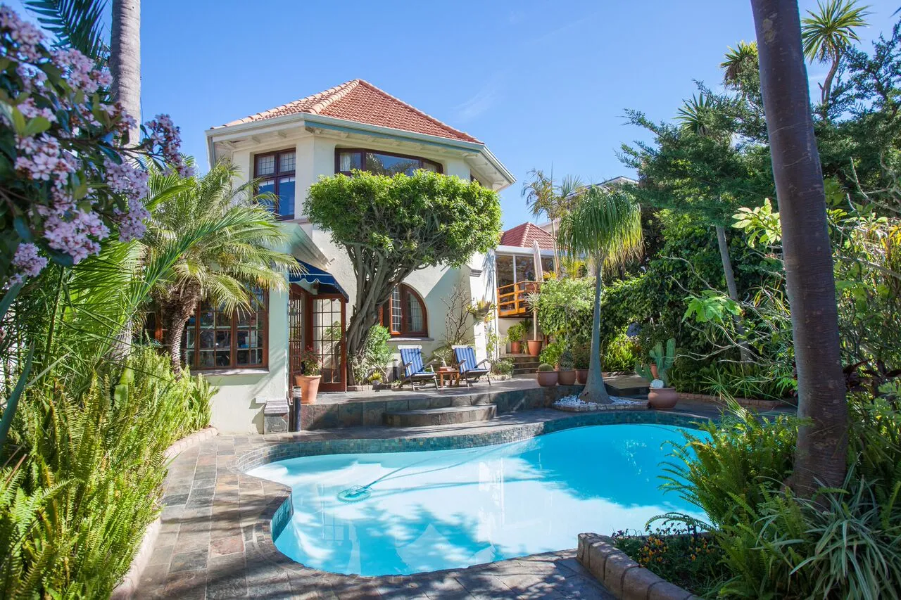 Mediterraneanstyle house with a swimming pool surrounded by lush greenery