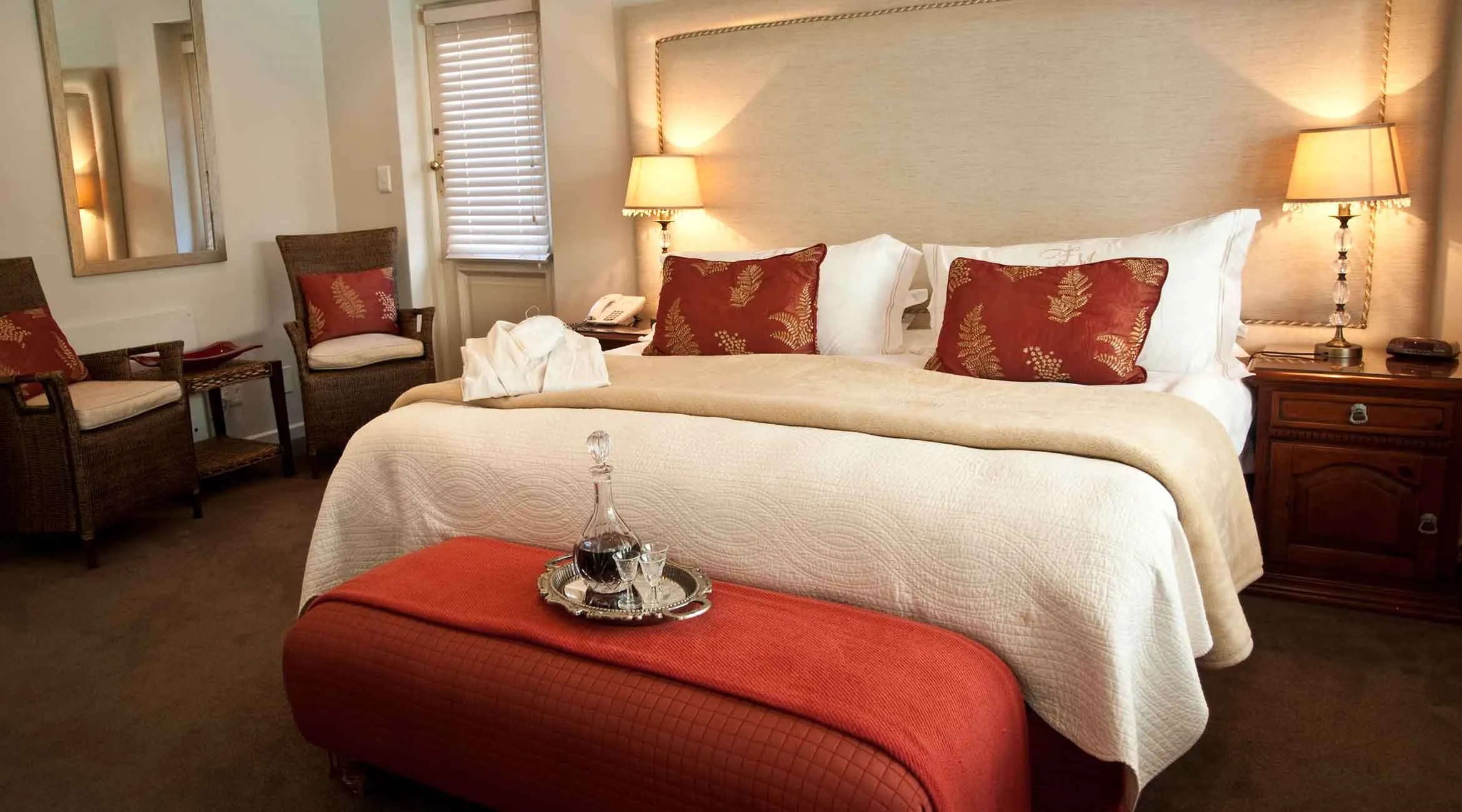 Cozy bedroom with a large bed two chairs and a red ottoman