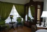 Greencurtained room with wooden furniture lamp and floral arrangement by window
