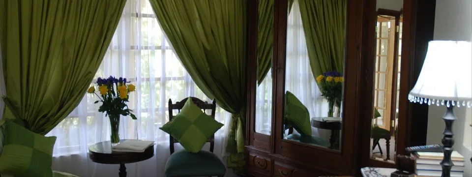 Green curtains floral arrangement and green cushions in a cozy room with a mirror