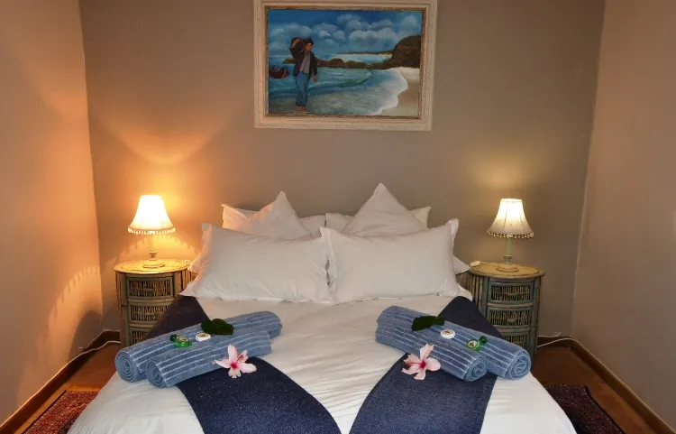 Cozy bedroom with a neatly made bed two bedside lamps and a beach painting