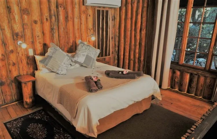 Wooden cabin bedroom with double bed pillows and towels on the bed