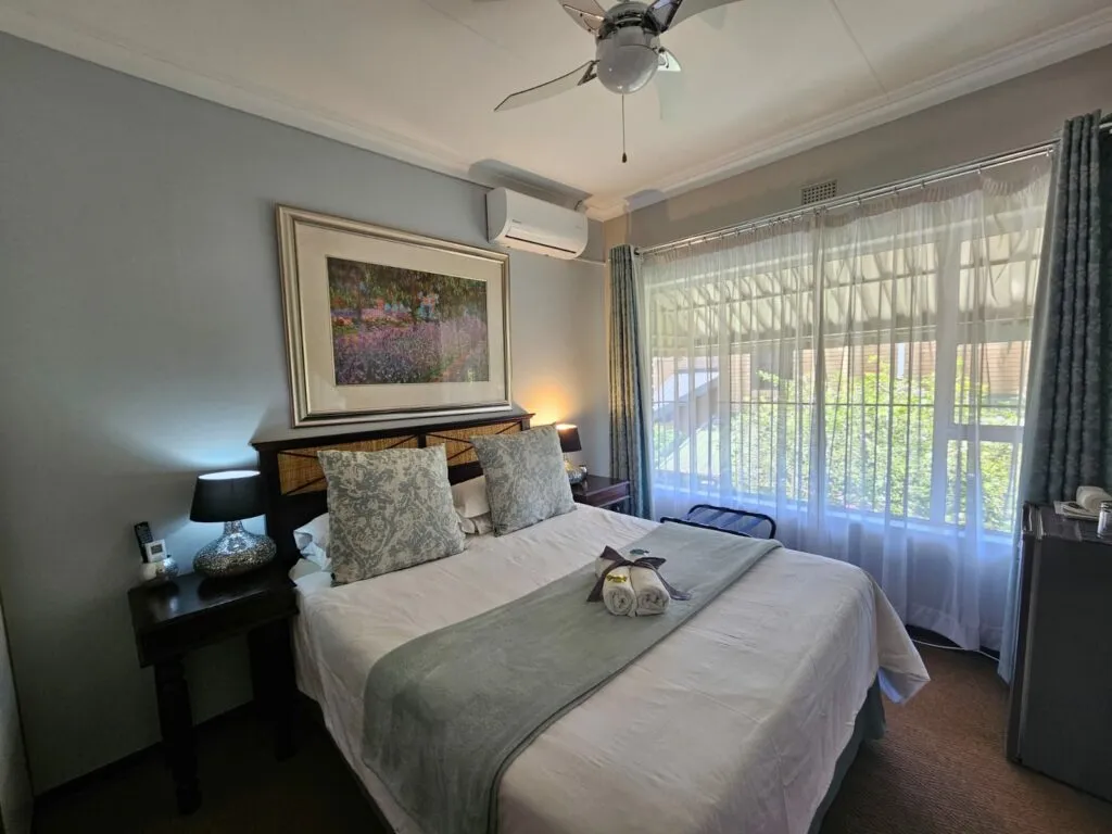 Neat bedroom with a double bed artwork and large windows with curtains