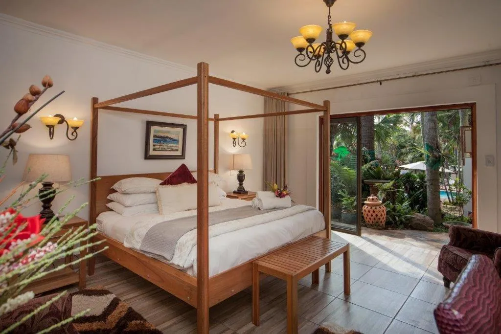 Fourposter bed in a bright bedroom with open doors to a garden view