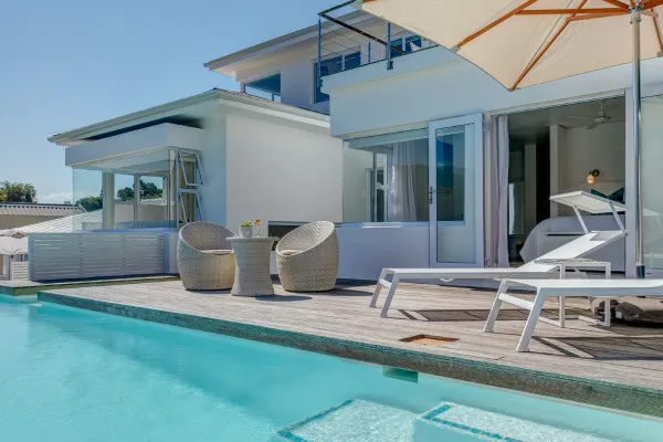 Modern patio with pool lounge chairs and wicker seating near a house