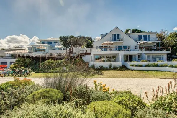 Modern white beach house with large windows and a wellmaintained garden