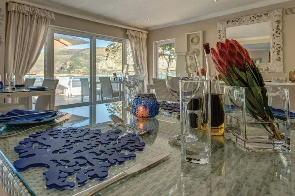 Dining table with red flowers glassware and ocean view through large windows