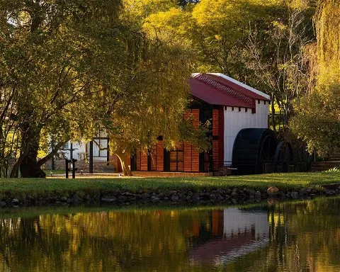 A red and white building by a pond with autumn trees