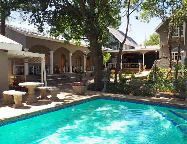 Swimming pool in a courtyard with tables chairs and a building in the background