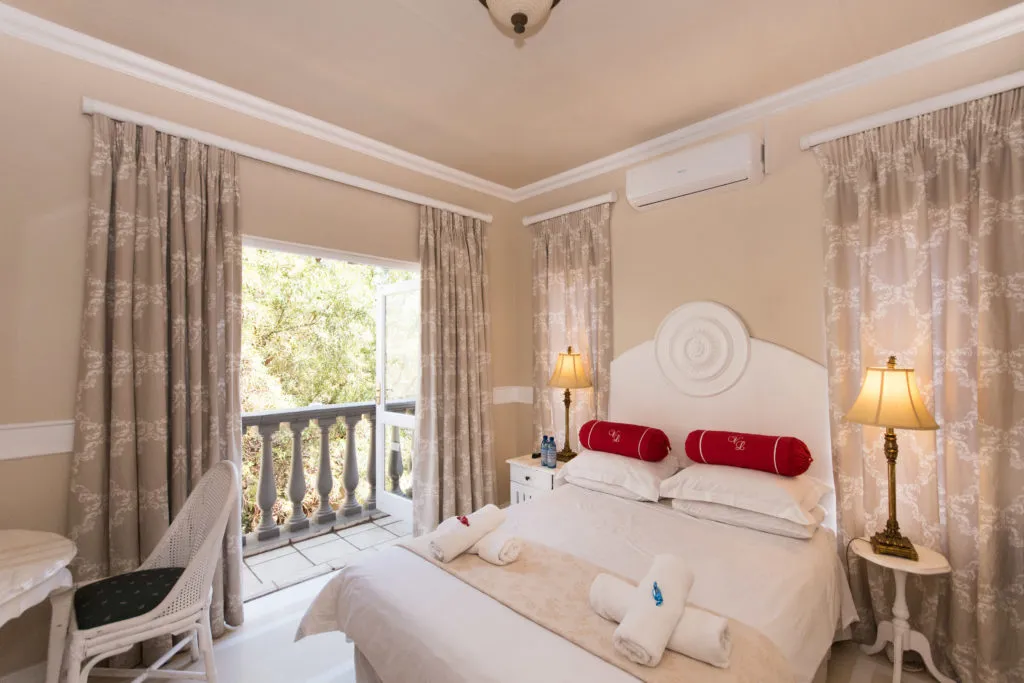 Cozy bedroom with white bed red pillows and open balcony view