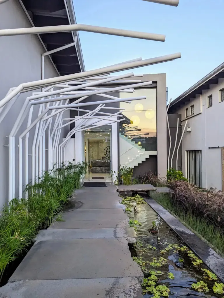 Modern building entrance with water feature plants and unique white structural elements