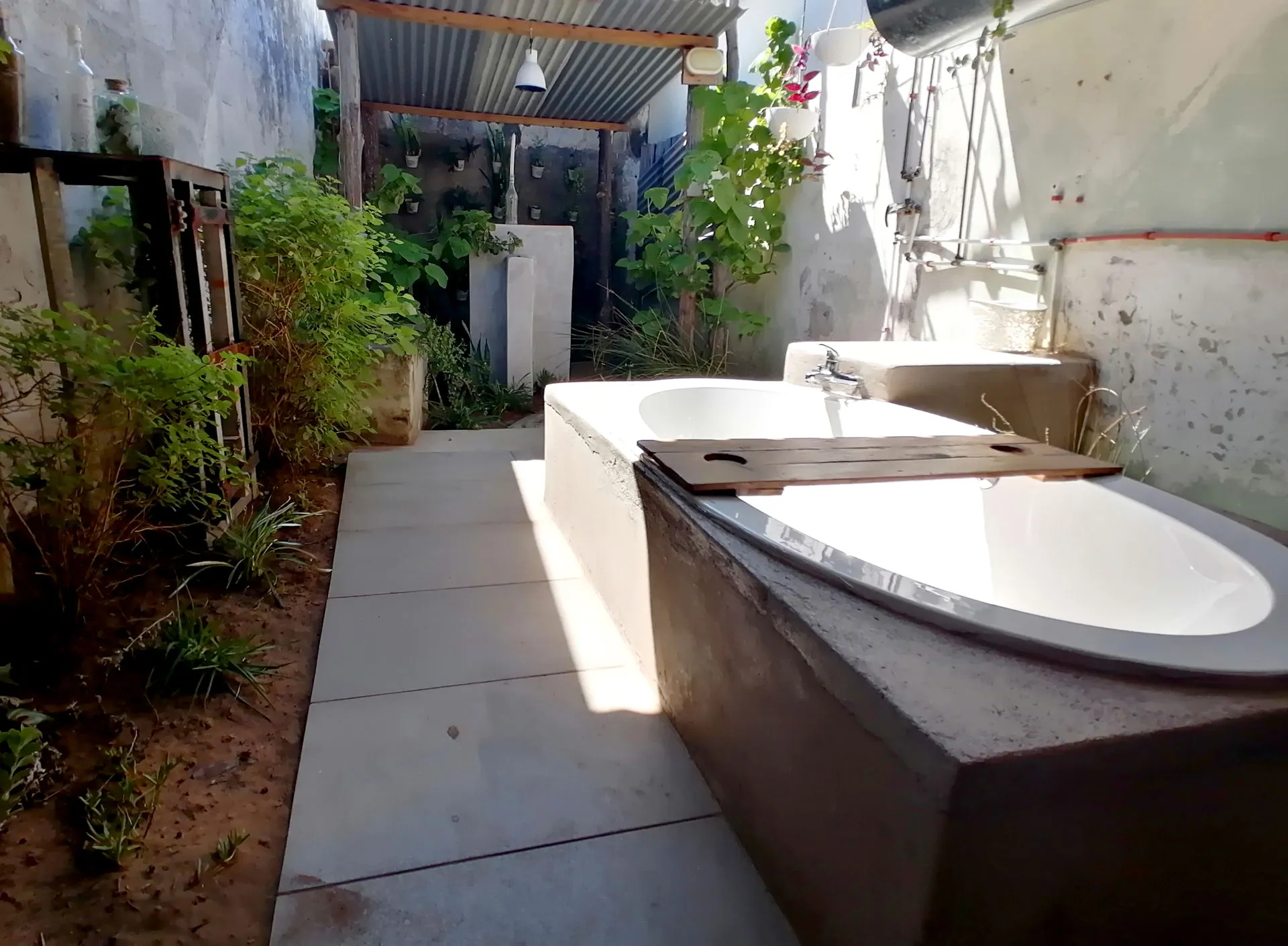 Outdoor bathroom with two concrete bathtubs and surrounding greenery