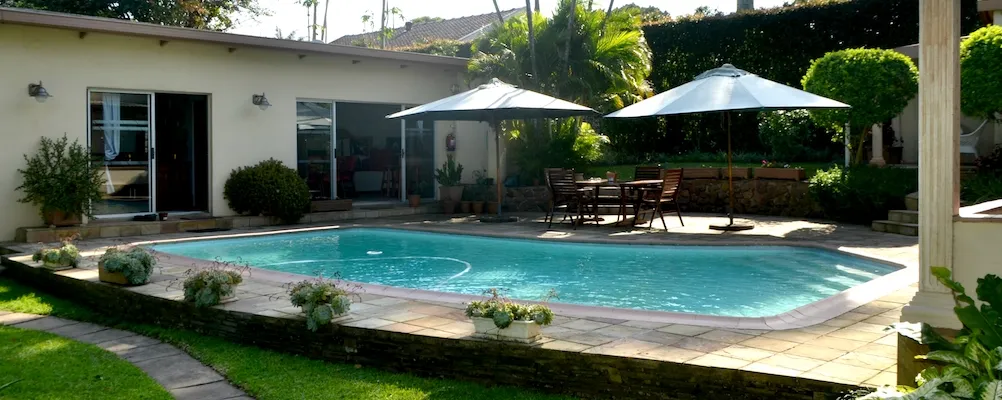 Swimming pool with patio furniture and umbrellas in a backyard setting