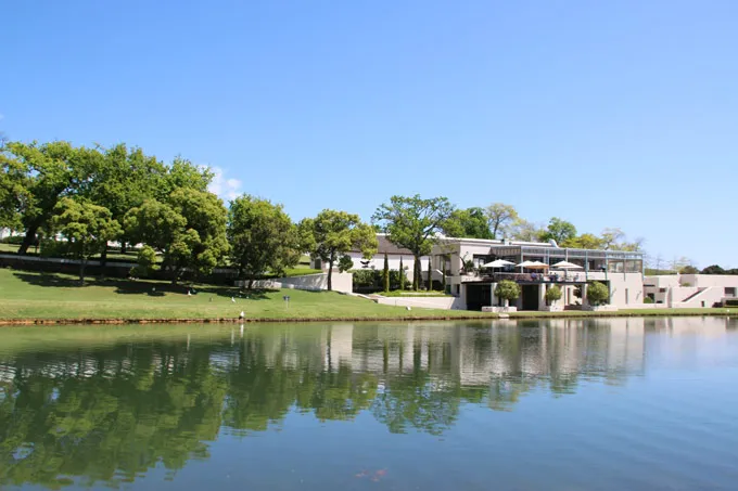 Modern building by a lake with trees and clear blue sky