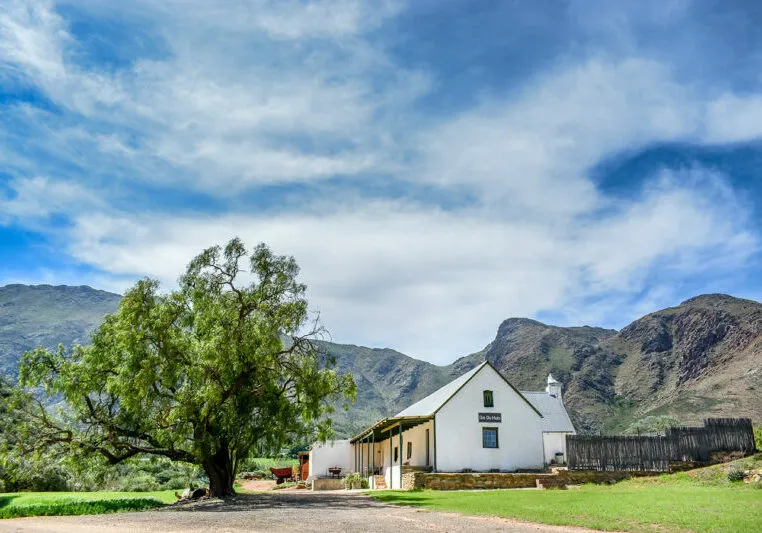 White house with tree in front mountains and blue sky in background