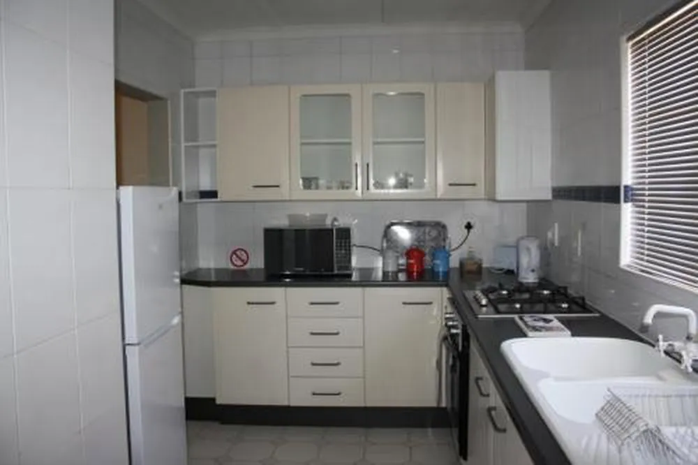 Small kitchen with white cabinets black countertops and appliances