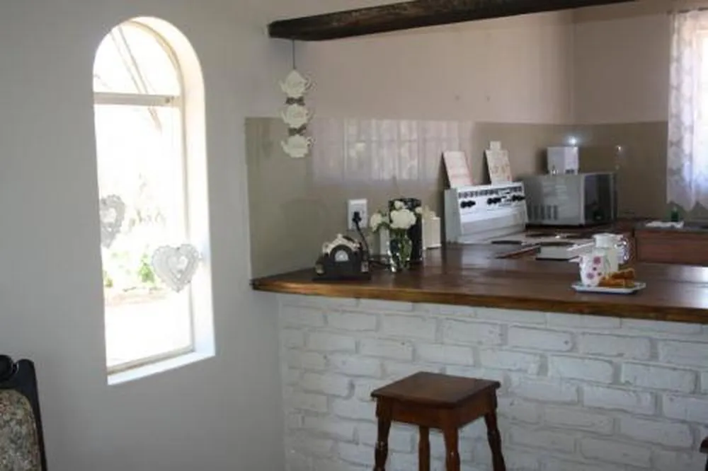 Kitchen counter with microwave kettle and stool white brick wall arched window